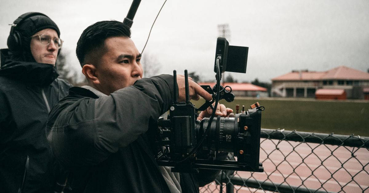 A dedicated cameraman capturing video at an outdoor sports field.
